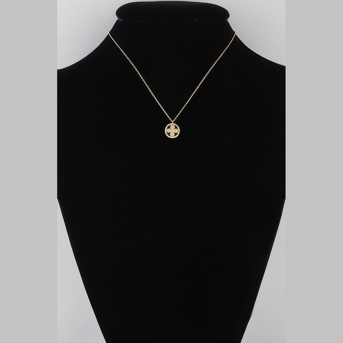 Jeweled Clover Pendant Necklace in gold with clear stones, displayed on a necklace bust