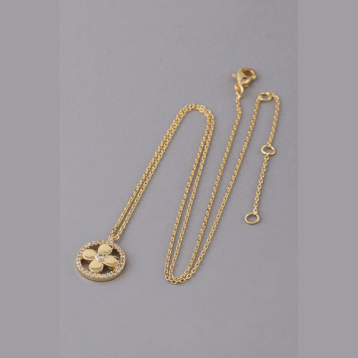 Jeweled Clover Pendant Necklace in gold with clear stones, flat lay