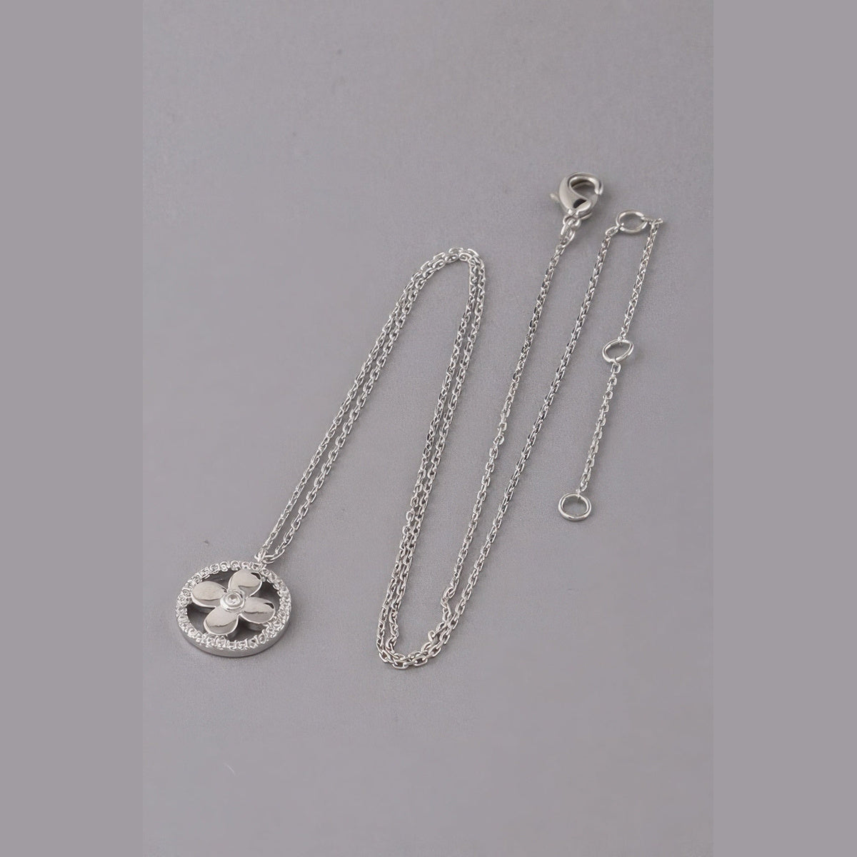 Jeweled Clover Pendant Necklace in silver with clear stones, flat lay