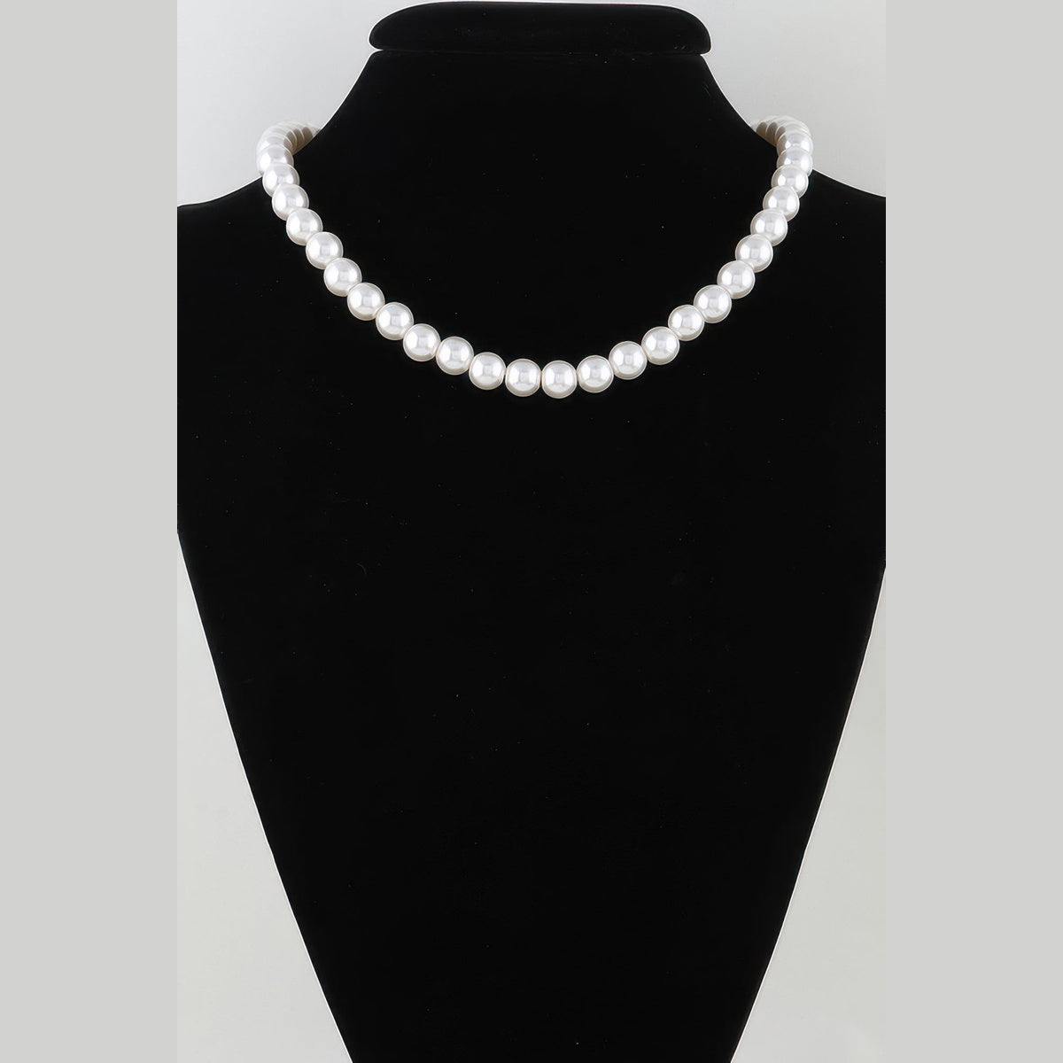 White pearl-effect necklace strand displayed on a black necklace bust