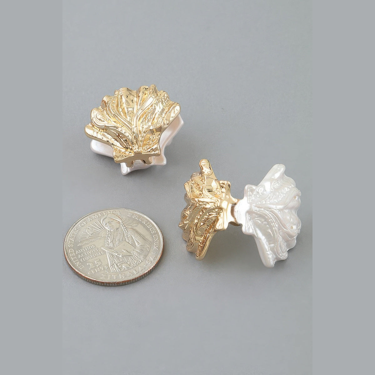 Two-Tone Clamshell Earrings in gold and pearl white, earring posts beside a coin for scale