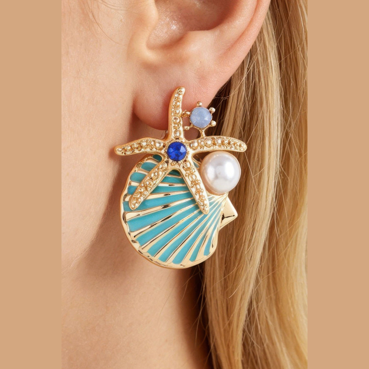 Starfish & Shell Statement Earrings in gold and aqua, close-up worn on the ear