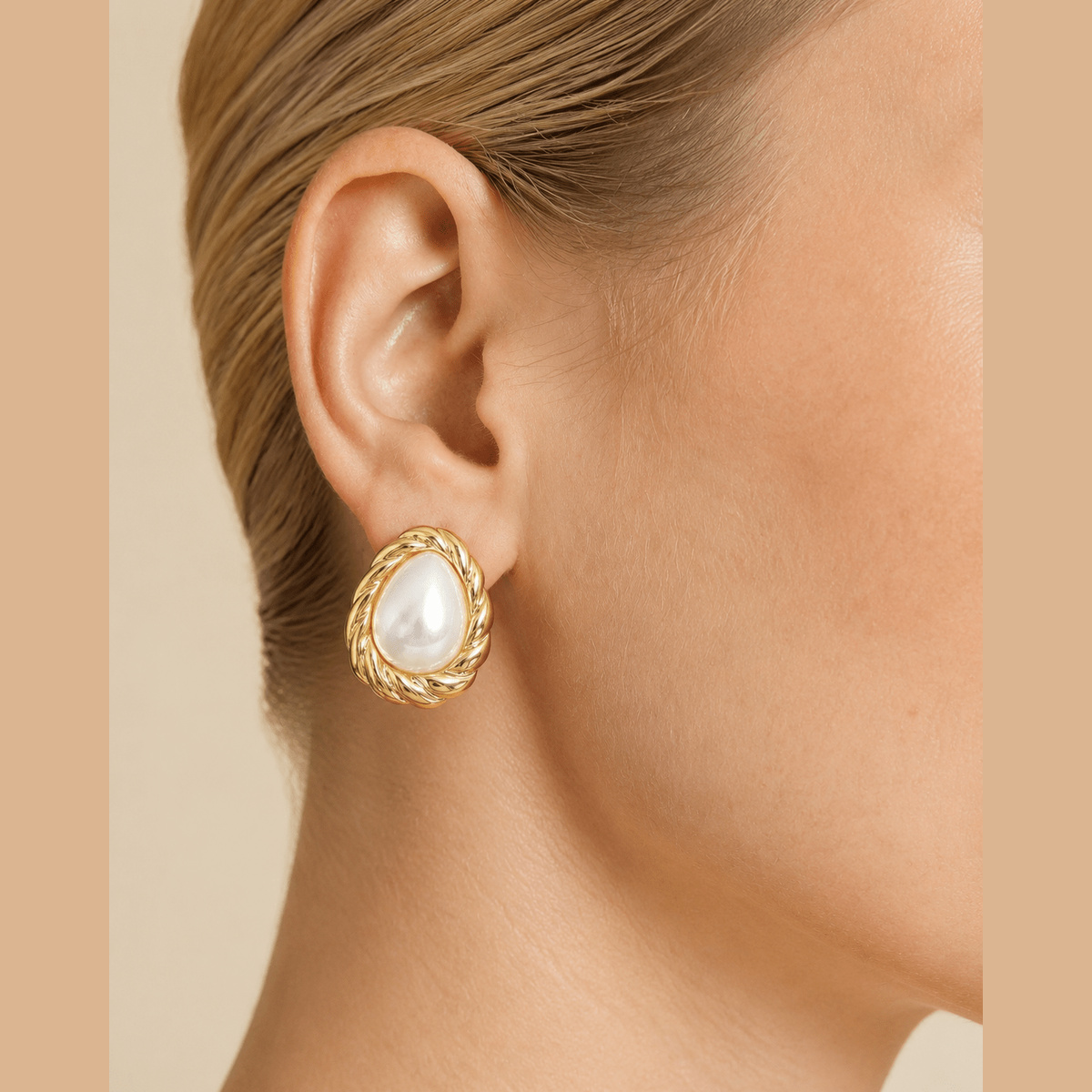 Twisted Frame Pearl-Effect Stud Earrings in gold and pearl white, worn on the ear