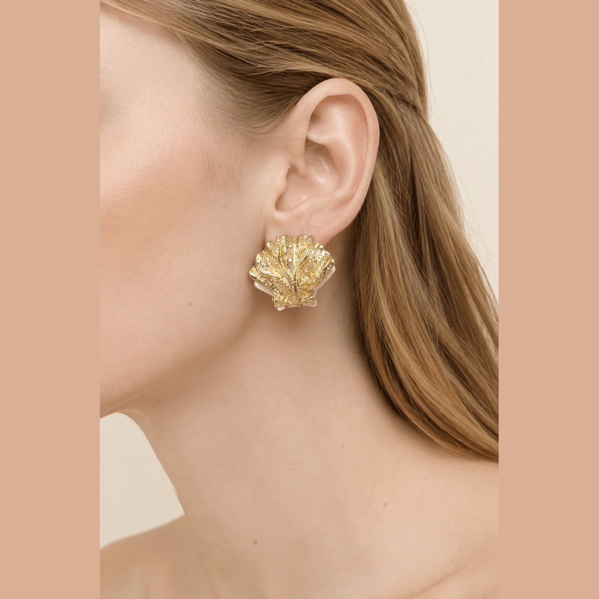 Two-Tone Clamshell Earrings in gold and pearl white, worn on the ear