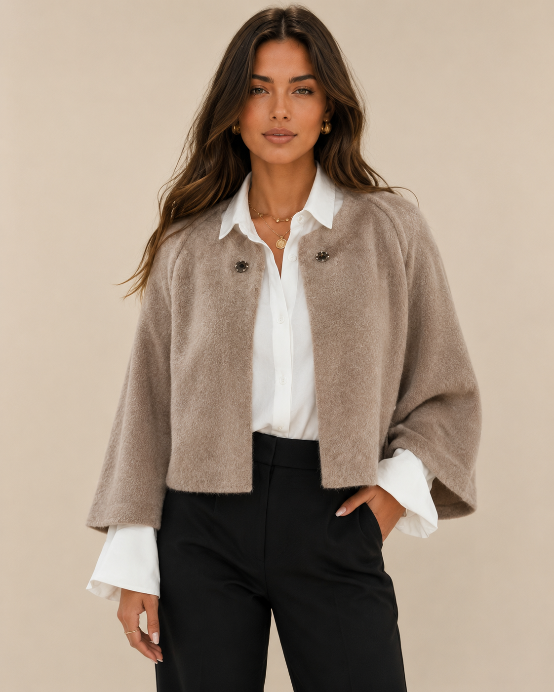 Woman wearing a cropped batwing cardigan on a warm beige studio background