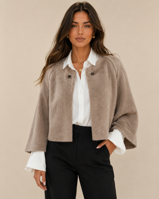 Woman wearing a cropped batwing cardigan on a warm beige studio background