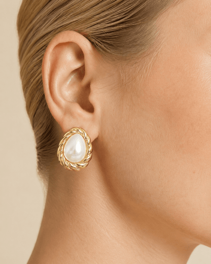 Close-up of a model wearing teardrop pearl-effect stud earrings with a twisted gold-tone frame