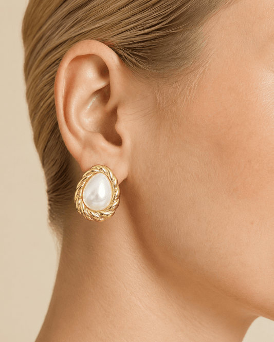 Close-up of a model wearing teardrop pearl-effect stud earrings with a twisted gold-tone frame
