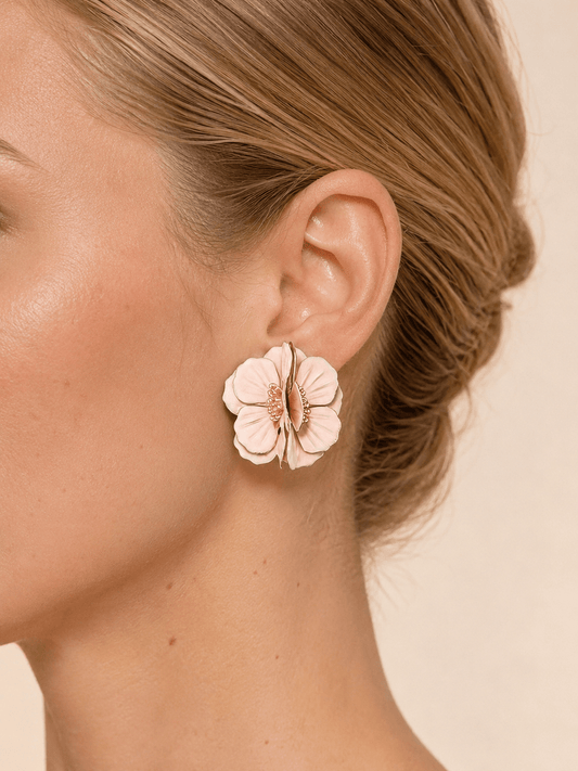 Close-up of a model wearing layered pink blossom statement earrings with a gold-tone center
