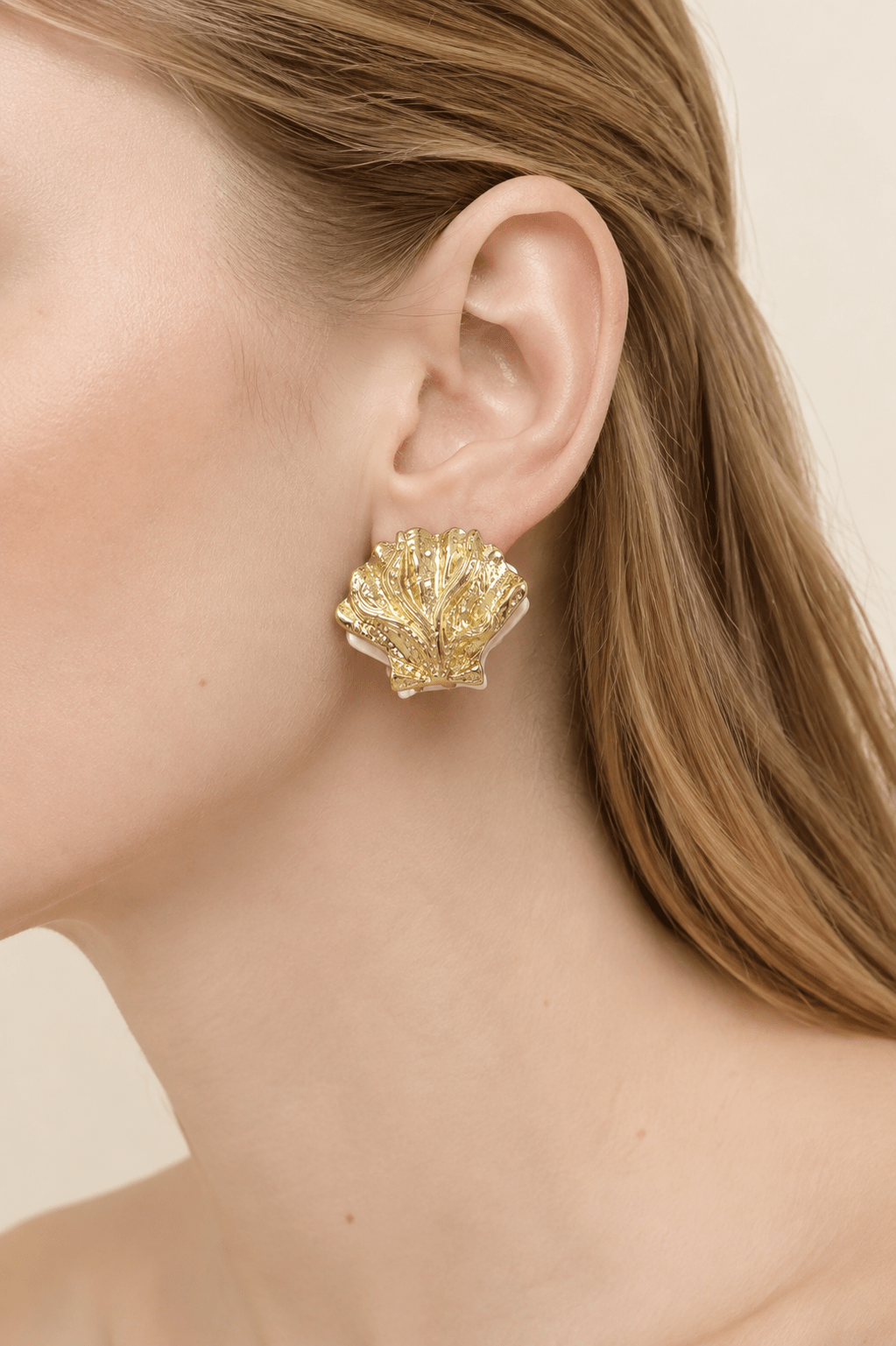 Close-up of a model wearing two-tone gold and pearl-effect clamshell earrings
