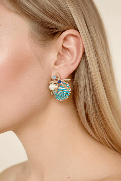 Close-up of a model wearing aqua starfish and shell statement earrings with pearl-effect accents