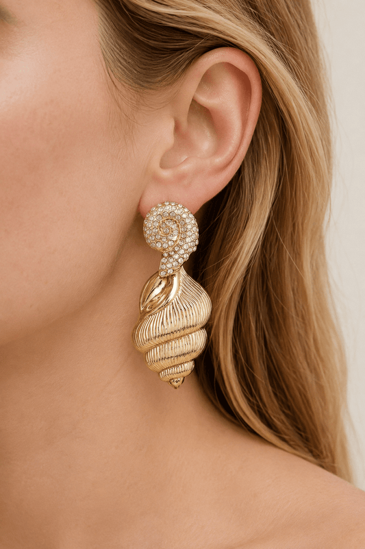 Close-up of a model wearing gold-tone conch shell drop earrings with clear stone accents