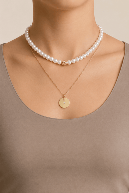 Pearl-effect and disc layered necklace worn on a fair-light skin model