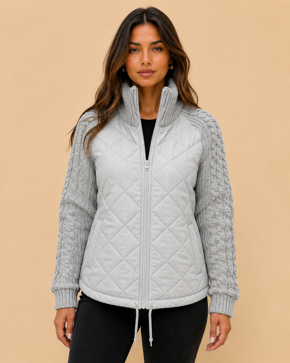 Woman wearing a quilted funnel-neck jacket with knit sleeves on a warm beige studio background